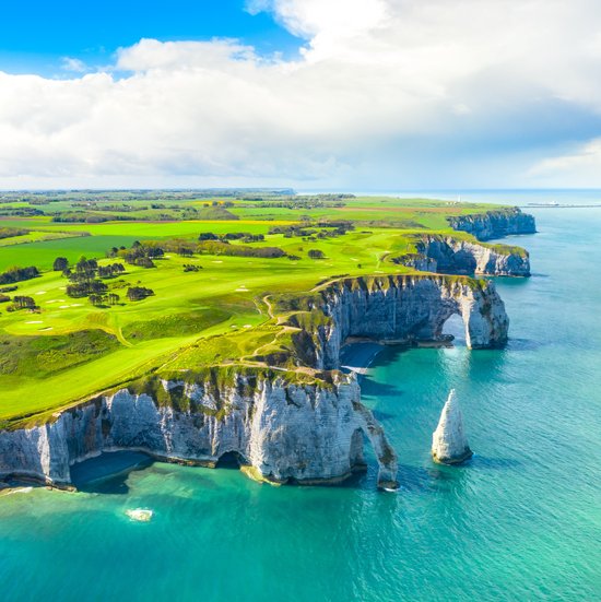 Cliffs of Étretat on the French coast, with dramatic rock formations and a blue sky in the background.