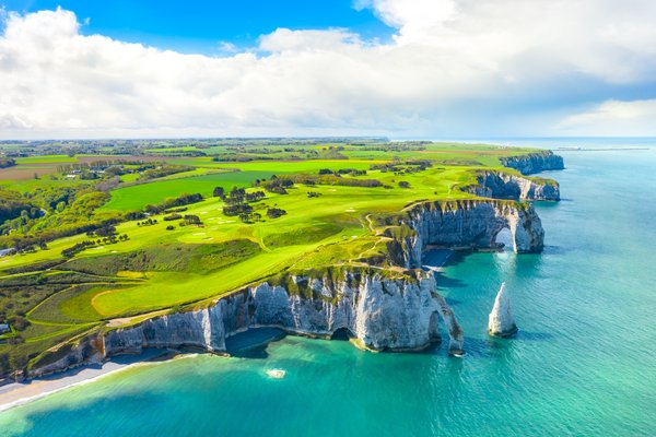 Cliffs of Étretat on the French coast, with dramatic rock formations and a blue sky in the background.