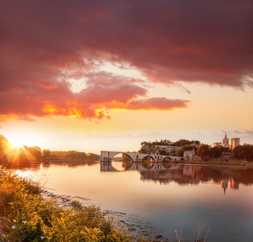 Sonnenuntergang über der historischen Brücke Pont Saint-Bénézet und der Stadt Avignon am Fluss Rhône