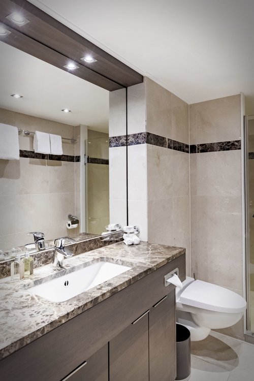 A brightly furnished bathroom on board the A-ROSA CLEA with a toilet, shower, and spacious wash area.