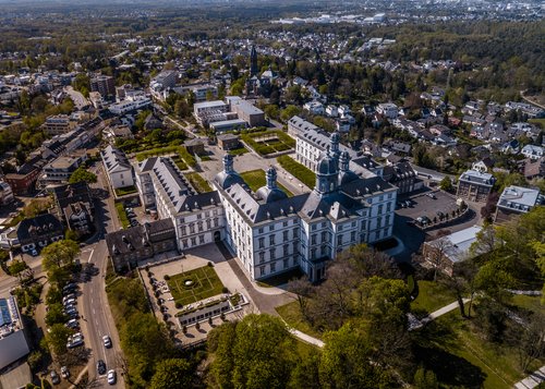 Luftaufnahme des Schlosses Benrath in Düsseldorf mit umliegenden Gärten und Wohngebieten im Frühling