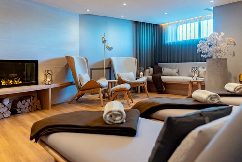 Stylish relaxation room on board the A-ROSA SENA with a fireplace, deck chairs, and cozy Scandinavian-style furnishings.