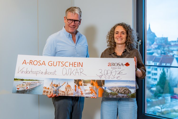 Two people, including A-ROSA CEO Rolf-Dieter Maltzahn, are holding a large voucher with the words ‘A-ROSA VOUCHER’ and the amount ‘€4,500’ written on it.