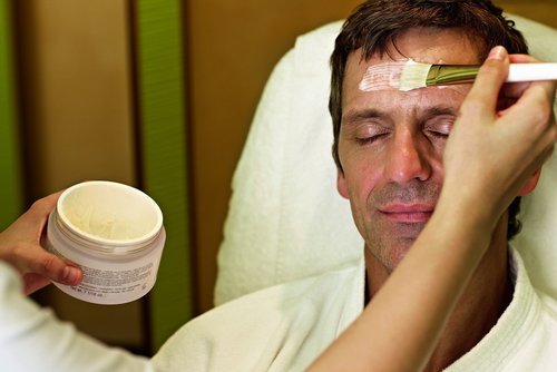 A man receives a relaxing facial treatment at SPA-ROSA while lying on a massage table.