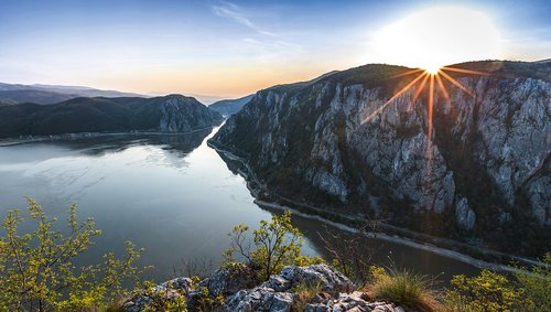 Panorama of the Danube Gorge at Weltenburg with sunrise over the steep cliffs. In the foreground, the vegetated cliff with a view of the Danube landscape.