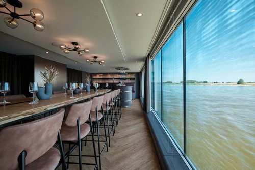 The stylishly furnished WINERY on board the A-ROSA SENA with elegant wooden and seating furniture.